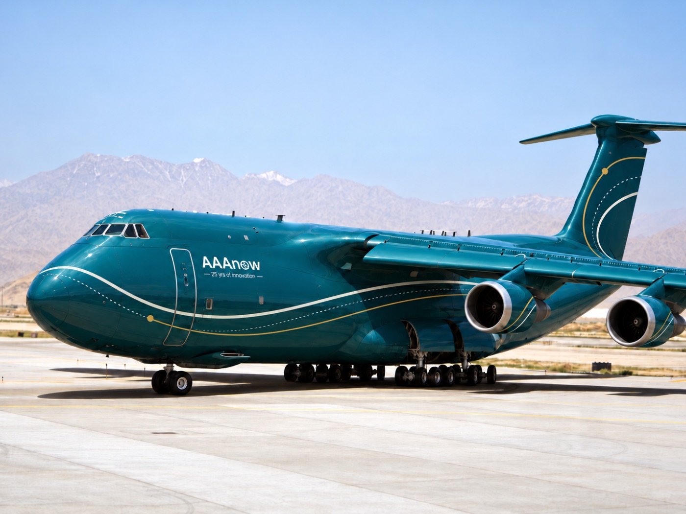 A very large 4-engine cargo aircraft painted in AAAnow teal, parked on a concrete apron under a clear sky with a desert mountain range behind. The AAAnow logo and the line 25 yrs of innovation sit on the forward fuselage beside the door, and cream and gold lines, one dotted, sweep from the nose along the body and curve up the tail.